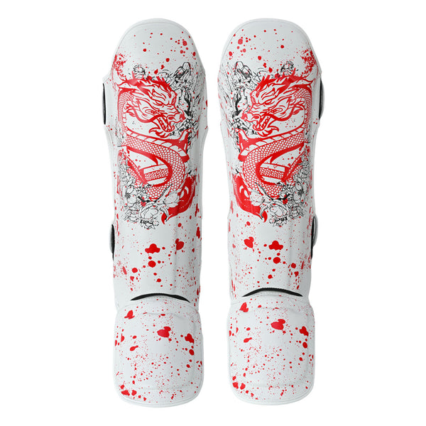 The SMAI Muay Thai Shin Instep Guard - White Dragon features bold red dragon graphics and red paint splatter on a white base, with EVA foam protection for superior comfort. Displayed side by side, facing upward.