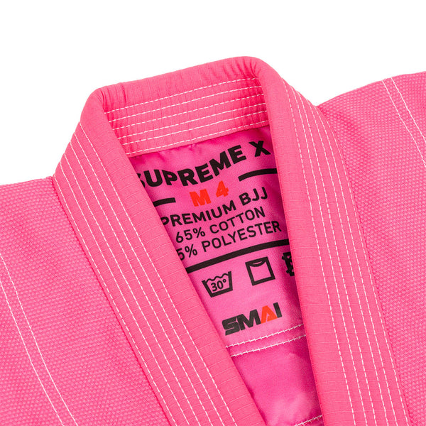 Close-up of the SMAI Supreme X Brazilian Jiu Jitsu Uniform in pink, with pearl weave fabric and an inner collar label showing size M4, fabric details, care instructions, and the brand name.