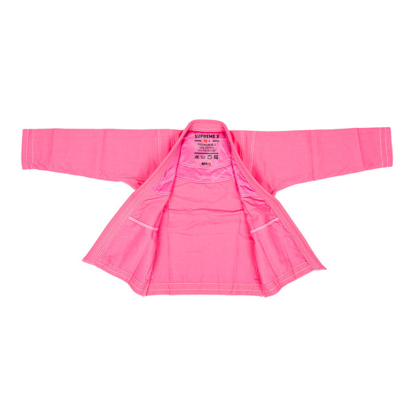 The Supreme X Brazilian Jiu Jitsu Uniform - Pink by SMAI is displayed flat with the front open, highlighting its durable Rip Stop fabric, detailed interior stitching, pockets, and a branded label inside the collar.