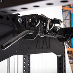 Close-up of the Cross Beam Logo Plate from the SMAI Vanta Series, a sleek black fitness cable machine equipped with multiple attachments, pulleys, and cables. This sturdy equipment stands against a blurred industrial background, highlighting its structural steel frame that ensures enhanced durability.