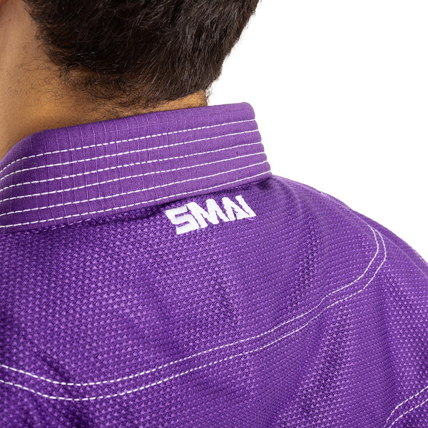 Close-up of a person wearing the Supreme X Brazilian Jiu Jitsu Uniform - Purple by SMAI, featuring reinforced stitching and "SMAI" embroidered in white on the collar; only the back of the neck and part of the head are visible.