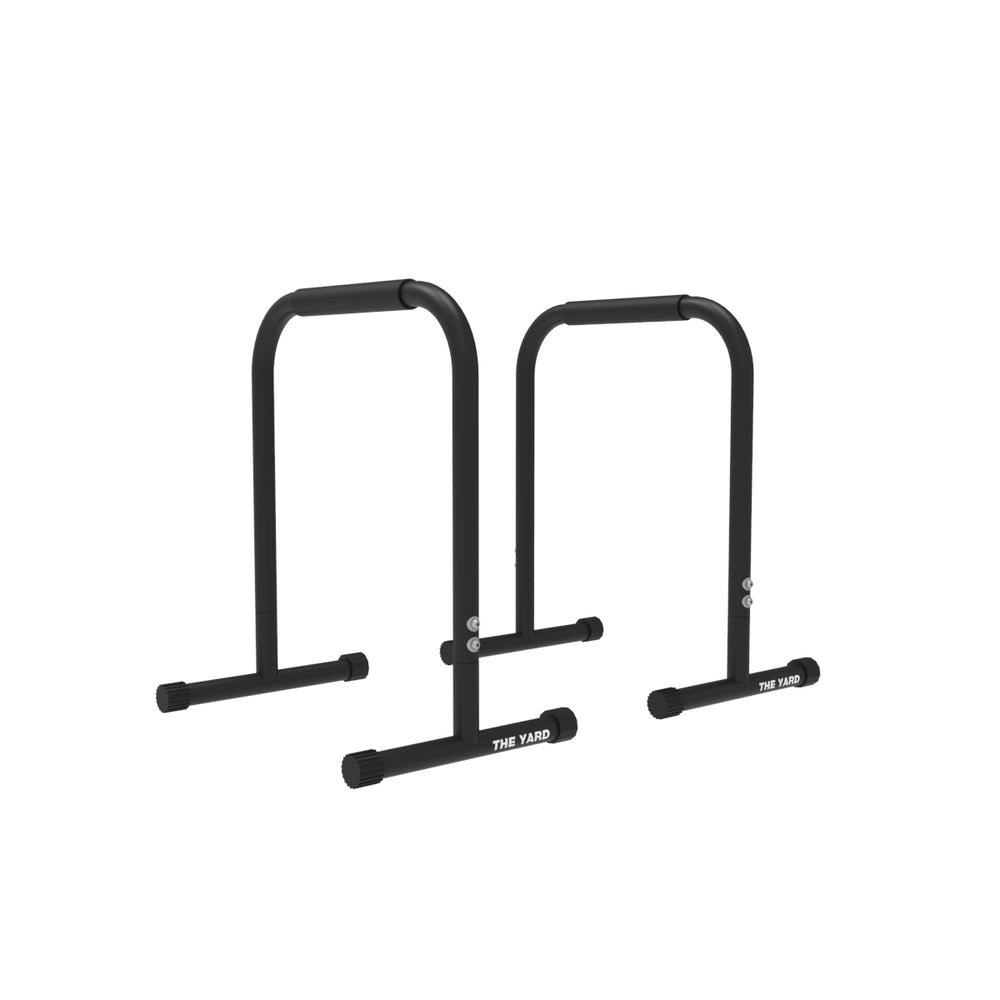 The Yard - Parallettes - Tall by SMAI are sturdy black gym equipment with padded grips and solid bases, ideal for dips and push-ups. "The Yard" branding appears on the front bottom section.