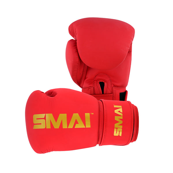 A pair of SMAI Gold Series Boxing Gloves in red and gold, featuring large gold "SMAI" branding on the wrist straps and superior shock protection, displayed on a plain white background.