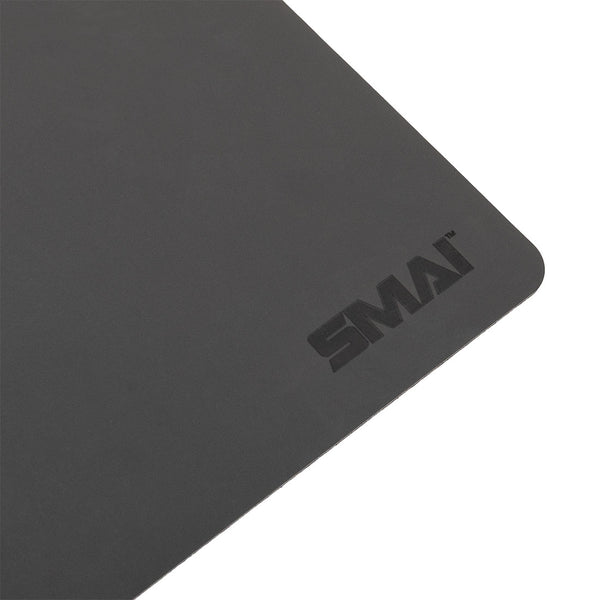 A close-up of the SMAI Pilates Reformer Carriage Topper / Protector, a rectangular black mat with rounded edges. The "SMAI" logo is printed near the corner, highlighting its sleek design for Reformer protection.