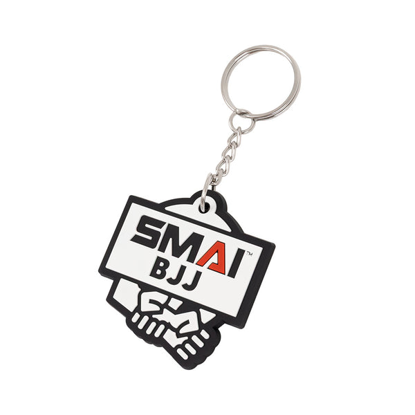 The SMAI BJJ Keyring - Rubber features the bold SMAI BJJ logo on a white background above two hands in a handshake, and comes with a sturdy silver ring.
