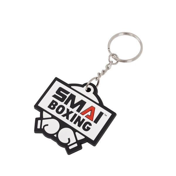 The SMAI Boxing Keyring - Rubber by SMAI features a metal ring and a durable rubber tag with "SMAI BOXING" above white gloves. The red "A" in "SMAI" highlights its unique look, making it ideal for boxing fans.