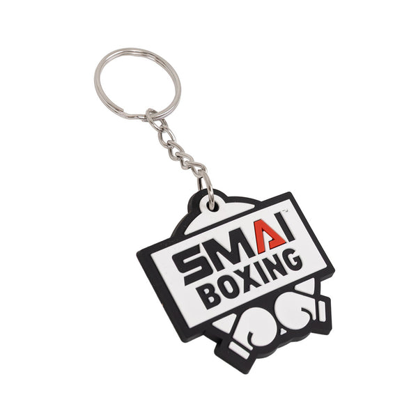 The SMAI Boxing Keyring - Rubber by SMAI features a rectangular tag with "SMA BOXING," a red "A," and two boxing gloves. This bold black, white, and red keyring is the perfect accessory for boxing fans.