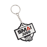 The SMAI Judo Keyring - Rubber by SMAI features a metal ring and chain, with a rubber emblem showing "SMAI JUDO" over a stylized hand gripping a belt, and the letter "A" highlighted in red.