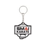 The SMAI Karate Keyring - Rubber by SMAI features a silver chain and rectangular rubber tag with "SMAI KARATE" in black and red above a white fist graphic outlined in black.
