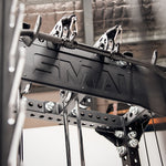 A close-up view of the Cross Beam Logo Plate from the Vanta Series showcases black gym pulleys with metal cables and handles. The structure is branded with "SMAI," set against an industrial-style ceiling background, emphasizing its robust design reminiscent of structural steel.