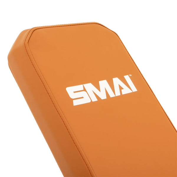 Close-up of the SMAI Commercial Adjustable Bench in tan, featuring padded upholstery with the white "SMAI" logo printed on the surface.