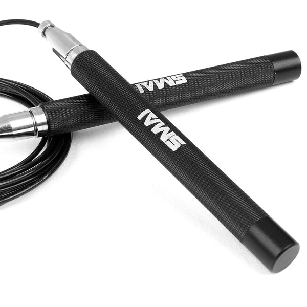 A close-up of the Speed Rope - Premium Black Steel featuring textured handles and adorned with the "SMAI" logo. The coiled jump rope highlights its German bearing and sleek metal handle ends against a white background.