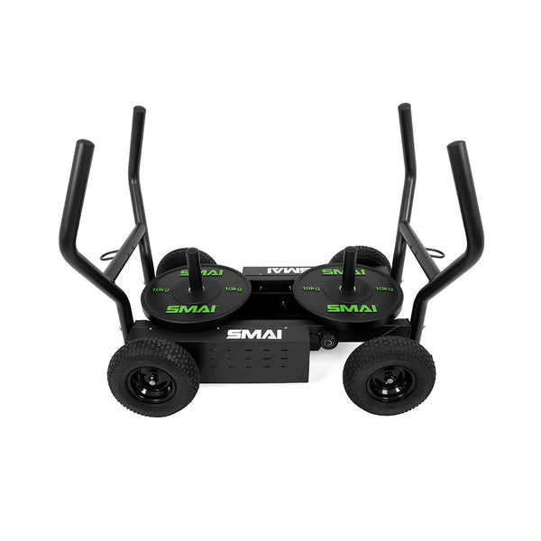 The SMAI All Terrain Resistance Sled is black, features four large wheels, two vertical push handles per side, and comes equipped with two green-labeled 10 kg weight plates on its platform. The versatile sled displays the "SMAI" brand name.