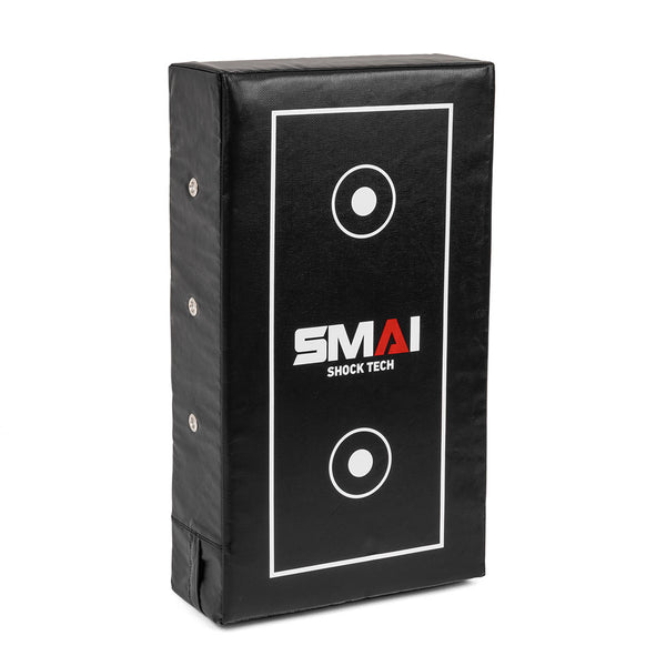 The SMAI Kick Shield - Shoc Tec Straight is a rectangular black shield with white target circles and lines, metal side rivets, and "SMAI SHOCK TECH" in the center. It features impact-absorbing foam for safe martial arts training.