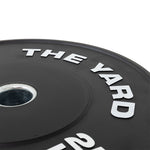 Close-up of SMAI's The Yard - HD Bumper Plates (Pair) - 15kg, crafted from high-density virgin rubber with "THE YARD" in raised white letters and a metal center ring—ideal for home gyms.