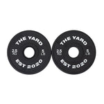 Two black SMAI plates from The Yard - 7.5kg Fractional Plate Set, labeled "THE YARD EST 2020," "2.5 KG," and "5 LB" in white—ideal fractional plates for micro-loading weight adjustments.