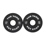 Two black SMAI Olympic barbell plates, each marked "THE YARD EST 2020," "1.25 KG," and "2.5 LB," are displayed side by side—part of The Yard - 7.5kg Fractional Plate Set, ideal for micro-loading in the gym.