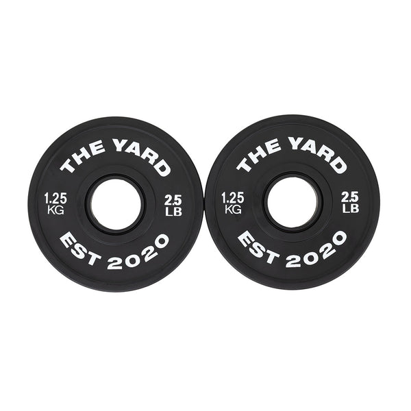 Two black SMAI Olympic barbell plates, each marked "THE YARD EST 2020," "1.25 KG," and "2.5 LB," are displayed side by side—part of The Yard - 7.5kg Fractional Plate Set, ideal for micro-loading in the gym.
