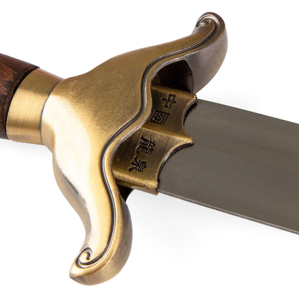 Close-up of the SMAI Tai Chi Sword Brass Fitting Ying Yang, featuring a curved brass handguard, wooden handle, and Chinese characters engraved near the base of its spring steel blade.