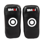 The SMAI Muay Thai Pad - Syntec Black (Pair) features two black rectangular pads with white target circles and the "SMAI" logo on top, made from durable synthetic leather, shown upright side by side against a white background.