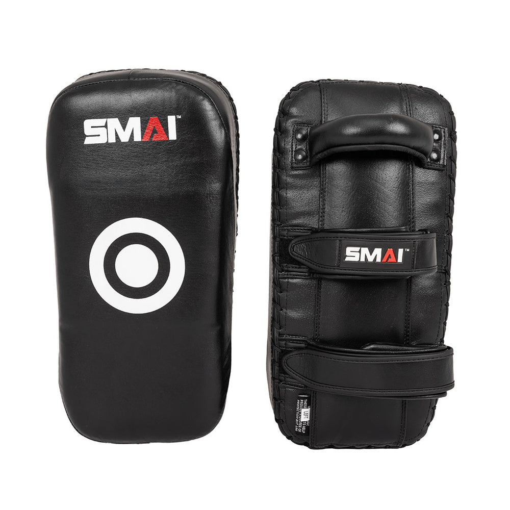 The Muay Thai Pad - Syntec Black (Pair) by SMAI features two black rectangular synthetic leather pads. One pad displays the SMAI logo and target circle; the other shows a handle plus two straps for a secure grip.