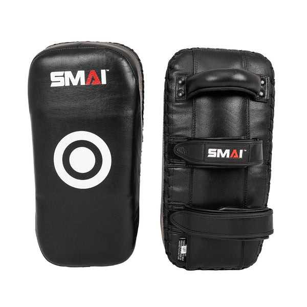 The Muay Thai Pad - Syntec Black (Pair) by SMAI features two black rectangular synthetic leather pads. One pad displays the SMAI logo and target circle; the other shows a handle plus two straps for a secure grip.