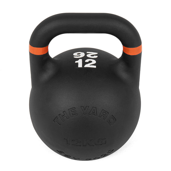 The Yard - Competition Steel Kettlebell 12kg by SMAI features a black finish, orange stripe near the handle, "12 KG" and "26" in white text, and embossed branding. Its uniform size is perfect for versatile kettlebell workouts.