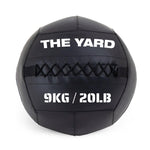 The SMAI The Yard - Wall Ball 9kg is a black wall ball made from recycled rubber, with "THE YARD" on top and "9KG / 20LB" below, visible stitching across the middle—ideal for your gym fitness routine.