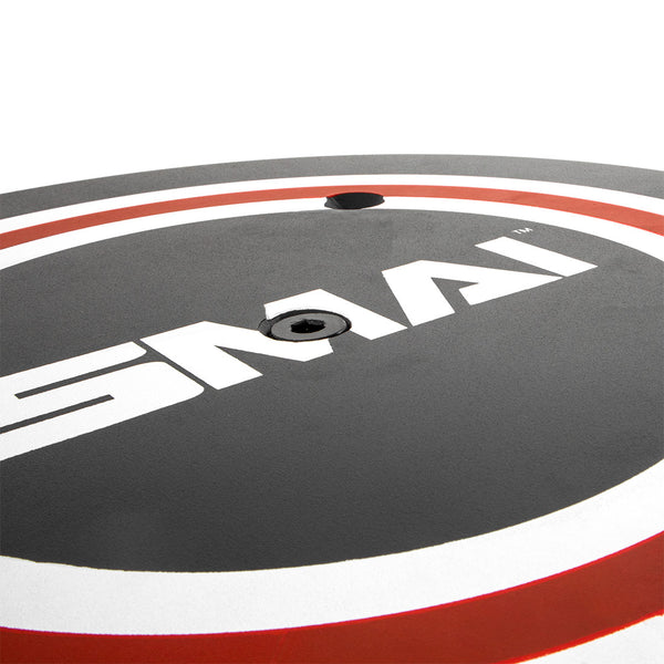 Close-up of an X-Frame - Wall Ball Target with a red outer ring and "SMAI" printed in white on the gray surface. The central hole is visible for loading onto a barbell, ideal for any commercial gym setup. Brand: No Sync To Channel Engine.