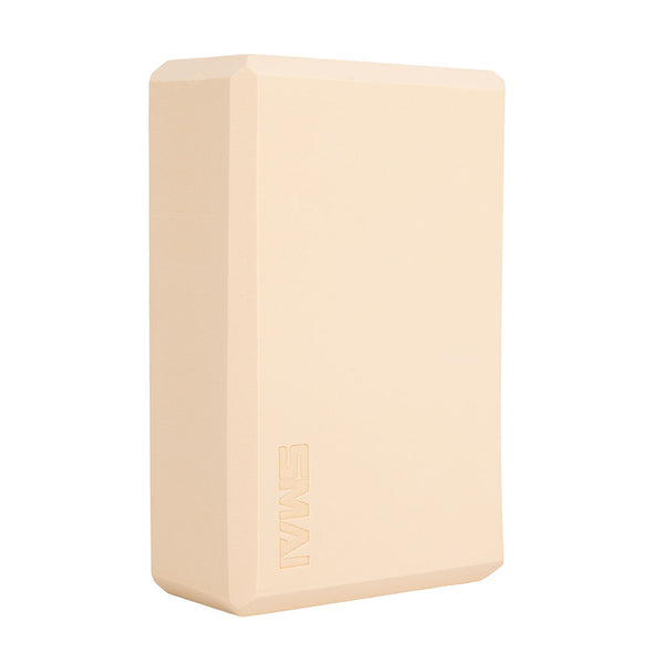 The SMAI Yoga Block - Camel is a beige rectangular foam block with beveled edges and "SMAI" embossed on one side—an essential accessory for added support in yoga practice.