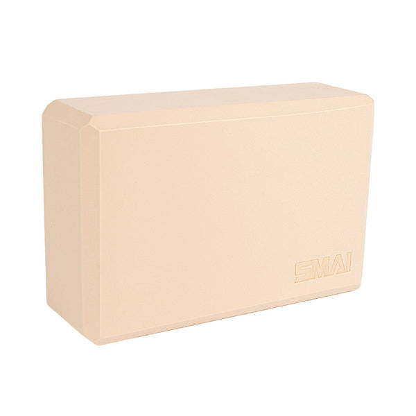 The SMAI Yoga Block - Camel is a rectangular, high-density foam block with beveled edges and a smooth beige surface. "SMAI" is embossed in one corner. The block stands upright against a white background.