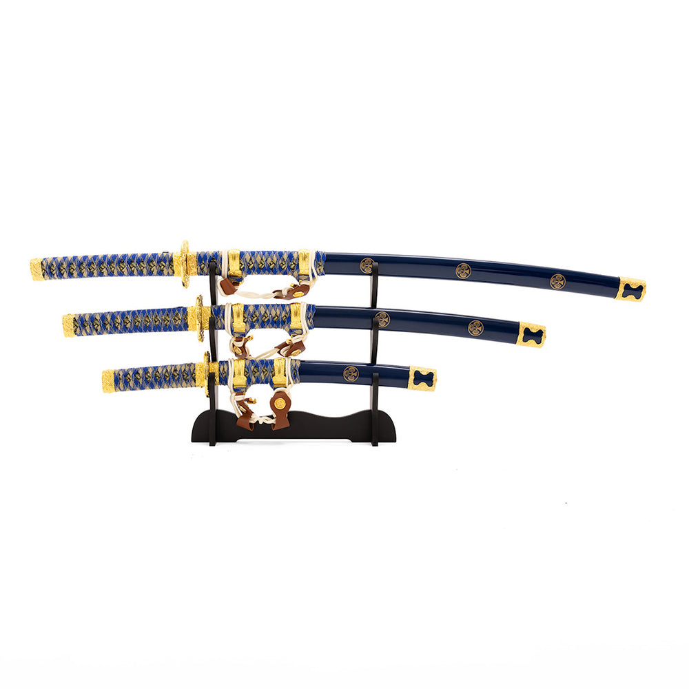 Showcase the SMAI Samurai 3pc Sword & Stand - Blue, featuring three Japanese swords with blue and gold handles and sheaths, elegantly arranged from largest to smallest on a sleek black stand.