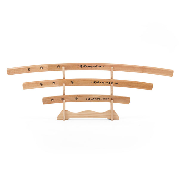 The SMAI Shirasaya 3pc Sword & Stand features three minimalist wooden Japanese swords of varying lengths with black kanji, displayed horizontally on a wooden stand against a white background.
