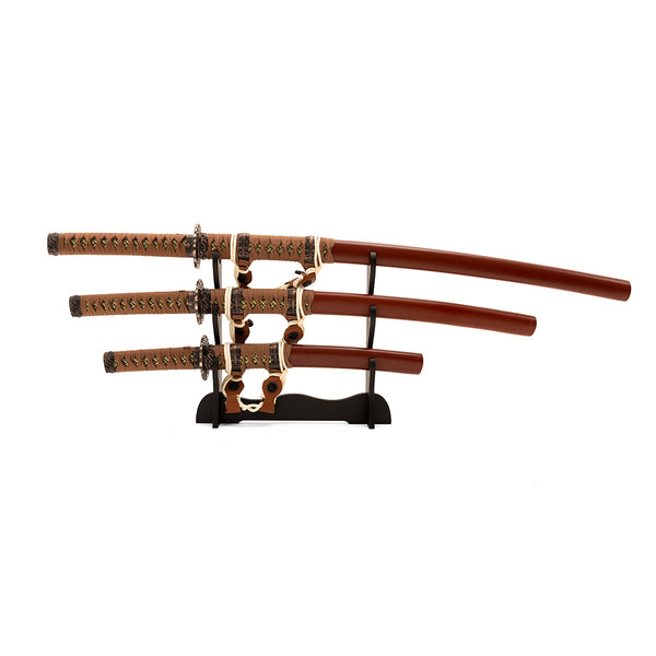 The SMAI Samurai 3pc Sword & Stand - Brown set includes a katana, wakizashi, and tanto with ornate handles and brown sheaths, beautifully displayed on a black wooden stand against a white background.