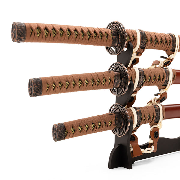 The SMAI Samurai 3pc Sword & Stand - Brown features three traditional Japanese swords with brown and tan wrapped handles, each sheathed and displayed horizontally on a black wooden stand.