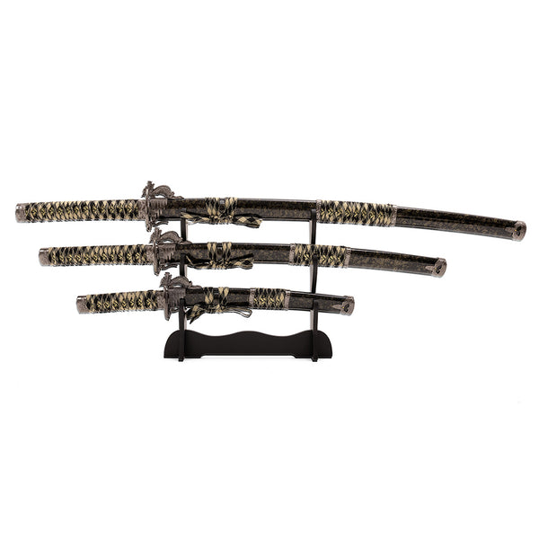 The SMAI Daisho 3pc Set with Stand - Desert Dragon features three Japanese display swords with dragon-themed designs and black and gold handles, elegantly showcased on a black wooden stand.