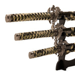 The SMAI Daisho 3pc Set with Stand - Desert Dragon features three elegant Japanese display swords with gold and black handles and dragon-themed guards, arranged horizontally on a black stand for striking decoration.