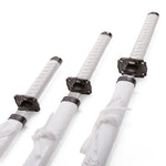 The SMAI White Samurai 3pc Sword & Stand features three white katanas of different lengths, each with ornate black guards and matching white scabbards tied with white cord—perfect for display.
