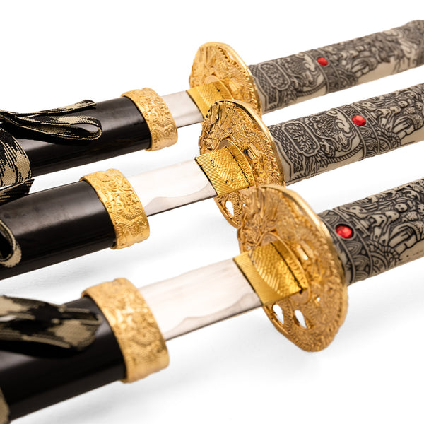 The Daisho - Highlander Display by SMAI showcases three ornate Japanese swords with gold and black handles, engraved guards, and intricate patterns, all partially unsheathed and displayed in a row.