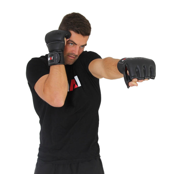 A man wearing a black t-shirt and SMAI Elite85 MMA Gloves in black throws a punch with his right hand while guarding his face with his left hand against a plain white background.