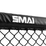 A close-up of the top section of a black chain-link fence with a padded cover, typically found in an MMA Cage Wall - Single Panel. The cover prominently features the brand name "SMAI" in white text.