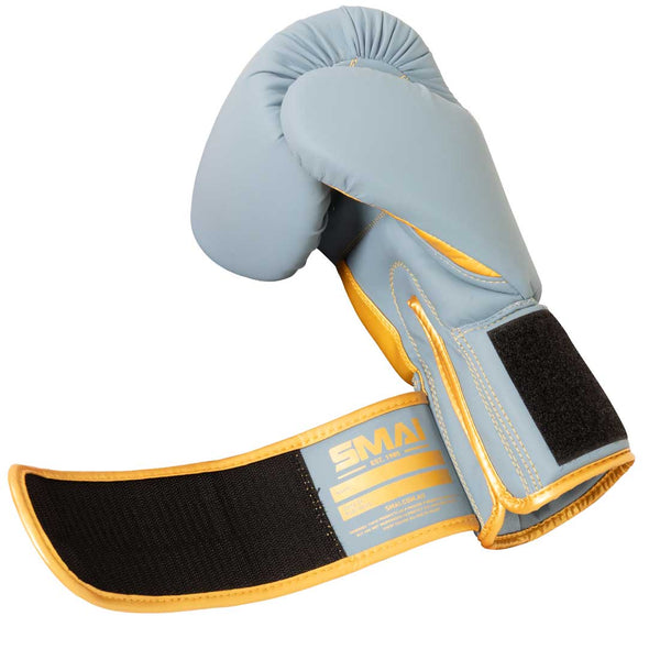 SMAI Gold Series Boxing Glove in Light Blue and Gold, featuring an open wrist strap that reveals the inside label and black Velcro, is expertly designed to deliver enhanced wrist support and reliable shock protection.