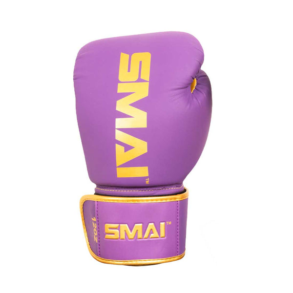 The SMAI Gold Series Boxing Glove in Purple/Gold features yellow "SMAI" branding on the front and wrist strap, and is designed for enhanced wrist support and superior shock protection. The glove is displayed on a white background.