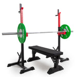 A gym bench press setup with a black bench, barbell, green weight plates, and a versatile Portable Squat Stand by Sale Item in red and black for support.