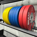 The SMAI Bumper Plate Toaster Storage Shelf - Vanta Series neatly holds colorful yellow, blue, and red "25 kg" SMAI bumper plates, providing organized and efficient storage against the gym wall.