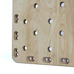 A close-up of the SMAI Monster Peg Board, crafted from light wood marine ply, displays rows of circular and oval holes in a grid pattern with smooth edges and natural grain texture.