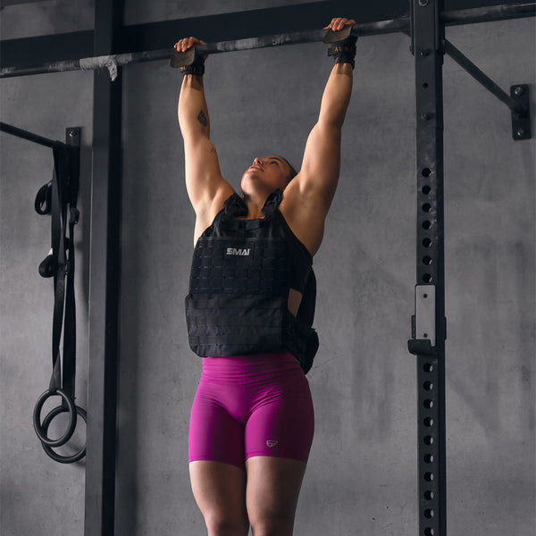 Woman hanging from pull up bar with a  SMAI weight vest adjustable