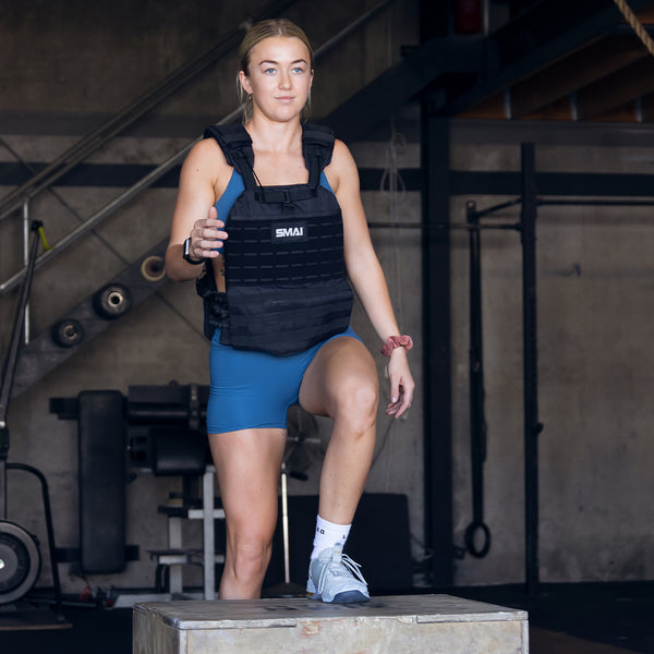 Woman stepping up on a plyometric box with a  SMAI weight vest adjustable