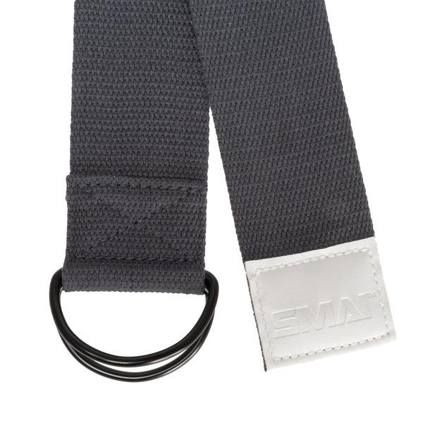 A close-up of the Yoga Strap Grey by Sale Item highlights its black cotton fabric with a double D-ring buckle, revealing its woven texture. Its adjustable length offers versatility, and a white stitched patch with raised text adds an intricate detail, making it ideal even for yoga practice.